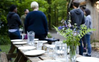 An image of a group and table set for a group meal, at Hazel Hill Wood.